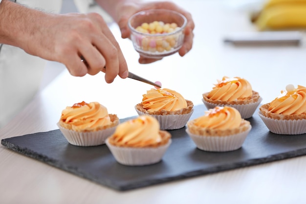 Mains masculines décorant des tartes avec des boules de sucre