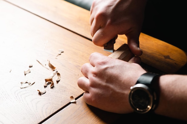 Les mains masculines découpent le bois avec un couteau
