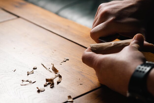 Les mains masculines découpent le bois avec un couteau