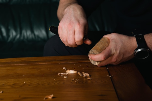 Les mains masculines découpent le bois avec un couteau