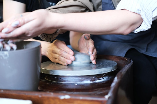 Des mains masculines et féminines fabriquent un vase d'argile Date dans l'atelier Photo horizontale