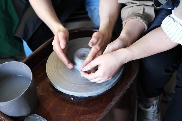 Des mains masculines et féminines fabriquent un vase d'argile Date dans l'atelier Photo horizontale