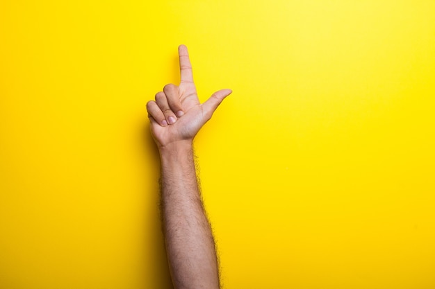 Les mains masculines pointent vers le haut sur fond jaune. Studio photo