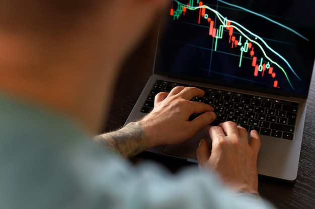 Les mains masculines surveillent les chiffres du marché boursier et le graphique sur l'ordinateur portable analyse des investissements concept de négociation