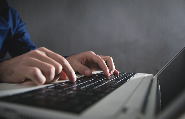 Mains masculines tapant sur le clavier de l'ordinateur.