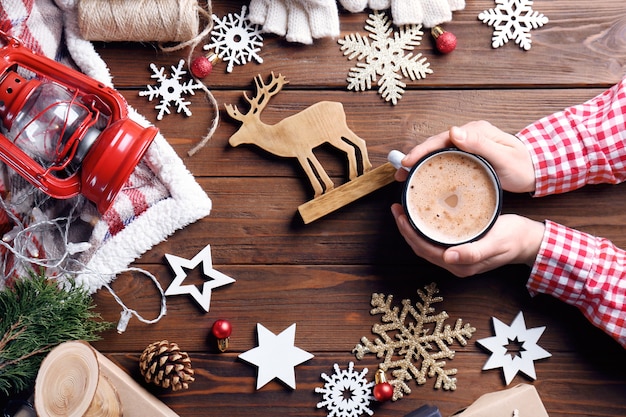 Mains masculines avec tasse de cacao et décorations de Noël sur fond de bois