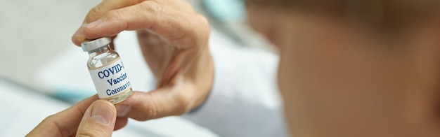 Mains masculines tenant une bouteille de vaccin covid