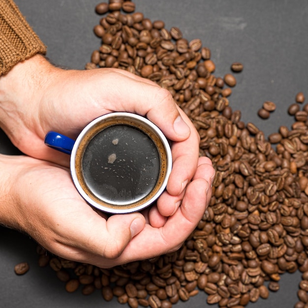 Les mains masculines tiennent le café sur un fond sombre