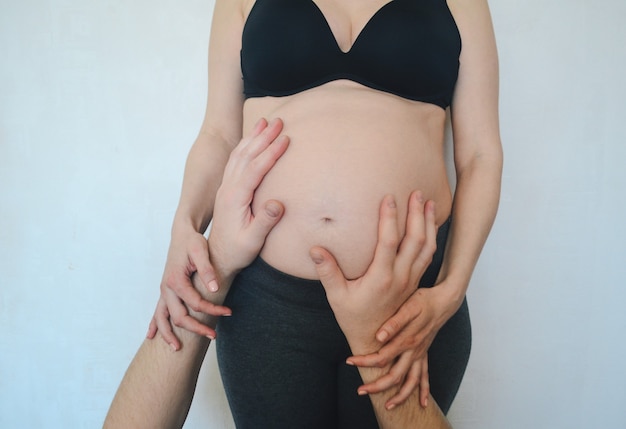 Mains masculines sur le ventre d'une femme enceinte grossesse familiale Concept
