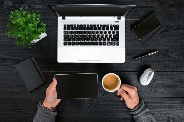 Mains masculines de vue de dessus de bureau en bois noir de hipster tapant sur un ordinateur portable