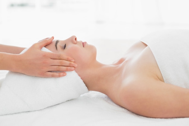 Mains massant le visage des femmes au spa de beauté