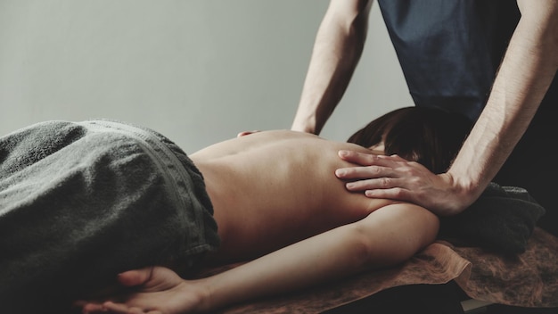 Mains de masseur faisant le massage des épaules dans le cabinet médical de la salle de fitness pour femme