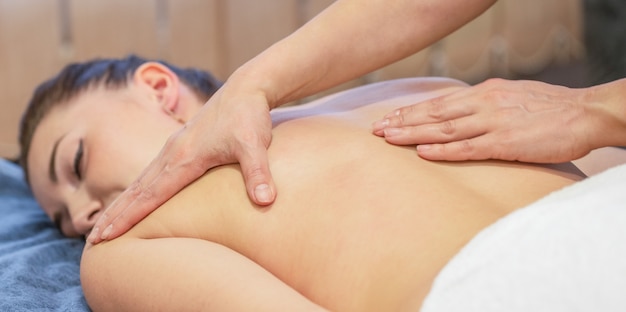 Mains de massothérapeute font un massage sur le dos de la jeune fille