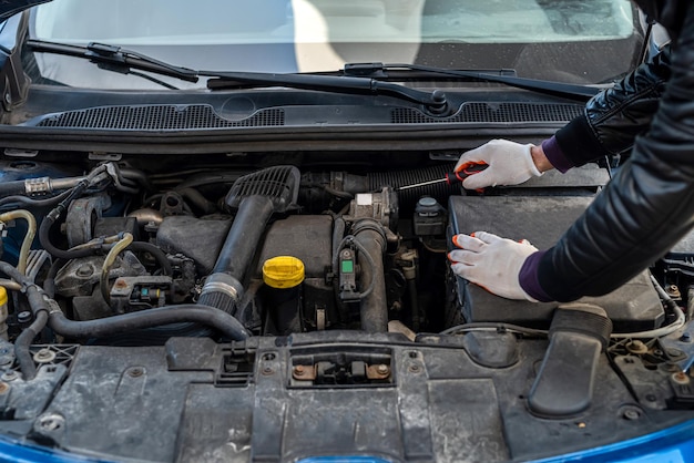 Photo les mains d'un mécanicien d'homme fort en gants réparent la voiture sous le capot