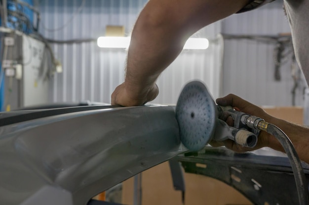 Les mains des mécaniciens manipulent la pièce de voiture avec une scie circulaire