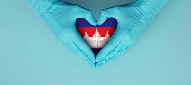 Photo les mains des médecins portant des gants chirurgicaux bleus faisant entendre le symbole de la forme avec le drapeau du cambodge