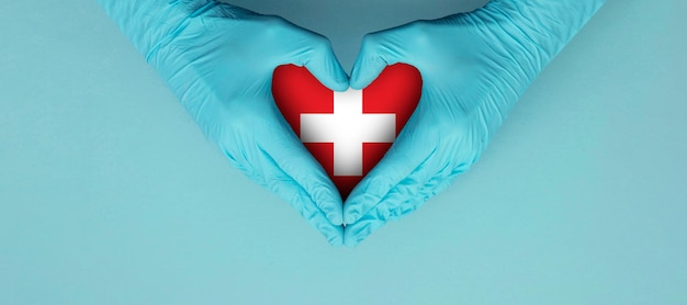 Les Mains Des Médecins Portant Des Gants Chirurgicaux Bleus Faisant Entendre Le Symbole De La Forme Avec Le Drapeau Suisse