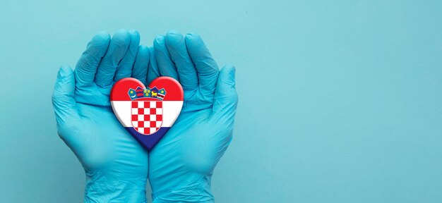 Mains de médecins portant des gants chirurgicaux tenant le coeur du drapeau de la croatie