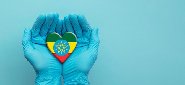 Mains de médecins portant des gants chirurgicaux tenant le coeur du drapeau éthiopien