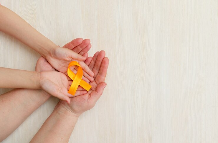 Les mains de la mère et de l'enfant tiennent un ruban orange sur fond blanc Journée mondiale de la sclérose en plaques