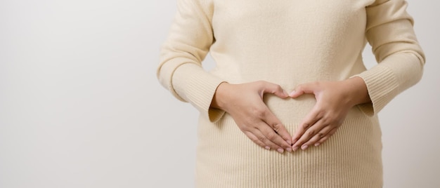 Mains de mère faisant la forme de coeur au ventre montrant le concept de grossesse