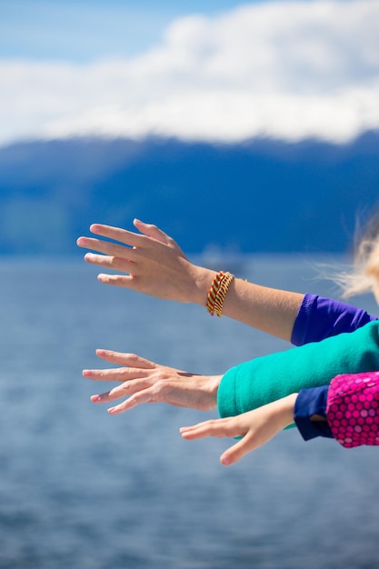 Mains de mère et de filles sur la mer au fjord