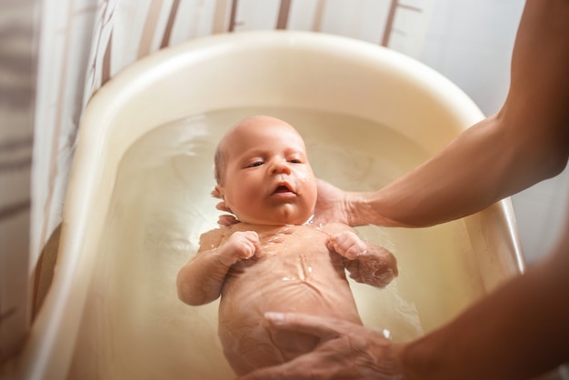 Mains d'une mère prudente tenant un petit bébé garçon