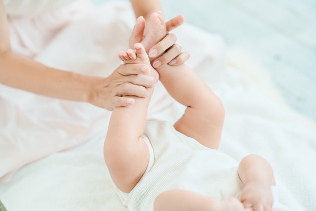 Les mains de la mère soutenant les pieds du bébé dans la chambre