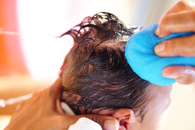 Les mains de la mère utilisent une éponge pour se baigner et laver les cheveux des nouveau-nés ou des petits enfants