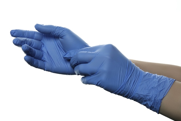 Mains mettant des gants médicaux, isolés sur blanc