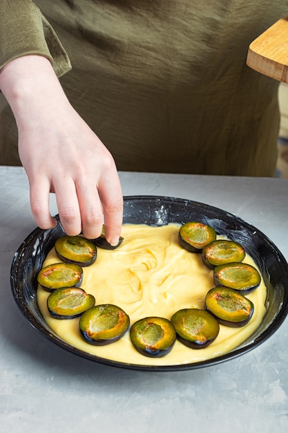 Mains mettant les moitiés de prune sur une tarte