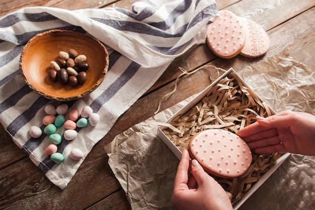 Les mains mettent le cookie dans une boîte avec des copeaux de bois.