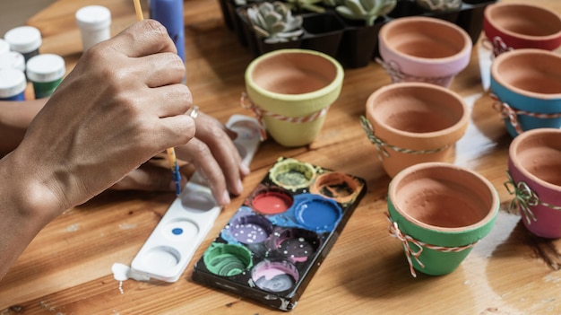 Mains d'une mulâtresse latine peignant des pots d'argile pour planter des plantes succulentes