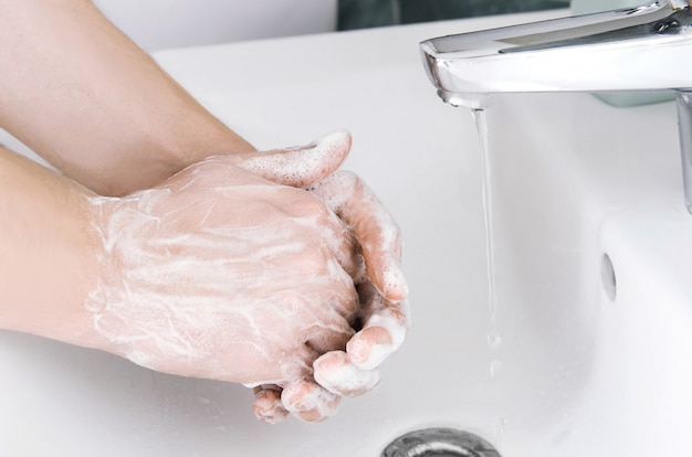 Mains de nettoyage masculines. Se laver les mains avec du savon pour se protéger du virus
