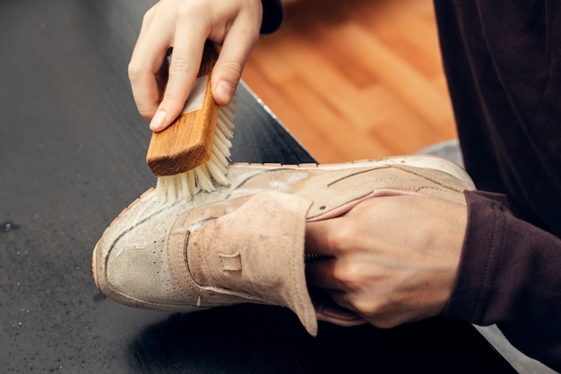 Mains nettoyant les baskets en daim