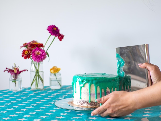 Les mains nivellent la crème avec une spatule et recouvrent le gâteau rond