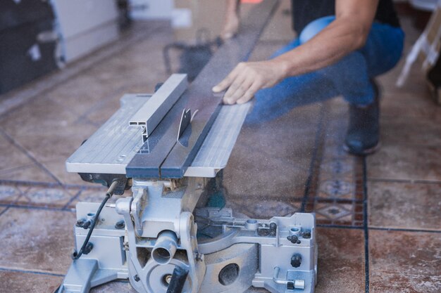 Mains non protégées d'un homme coupant une planche avec un disque électrique