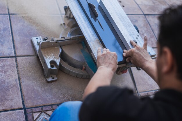 Mains non protégées tenant une planche coupée avec un disque électrique