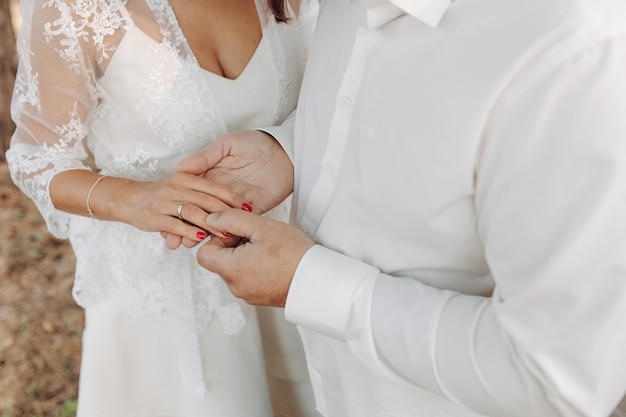 Mains oMains de jeunes mariés avec des anneaux de mariage et un bouquet de mariage.