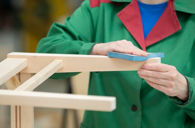 Les mains d'un ouvrier d'une usine de bois broient des chaises en bois naturel