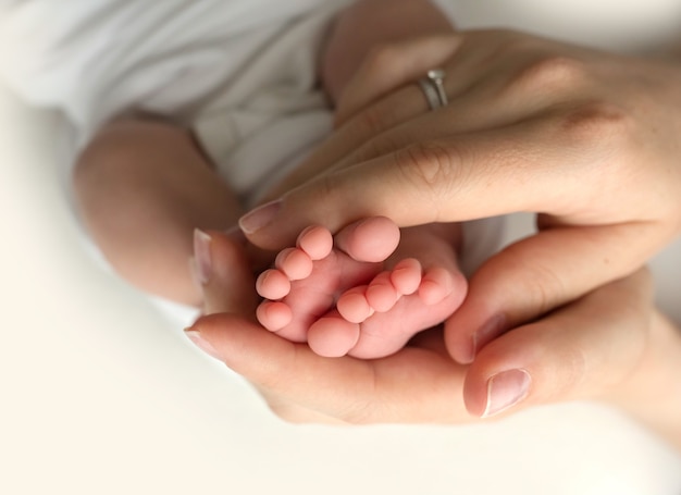 Mains des parents. Les jambes, les pieds du nouveau-né entre les mains de maman et papa. photo de haute qualité