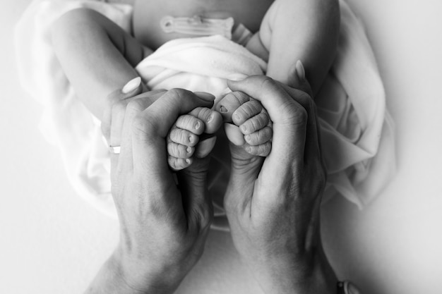 Mains des parents. Les jambes, les pieds du nouveau-né entre les mains de maman et papa. photo de haute qualité