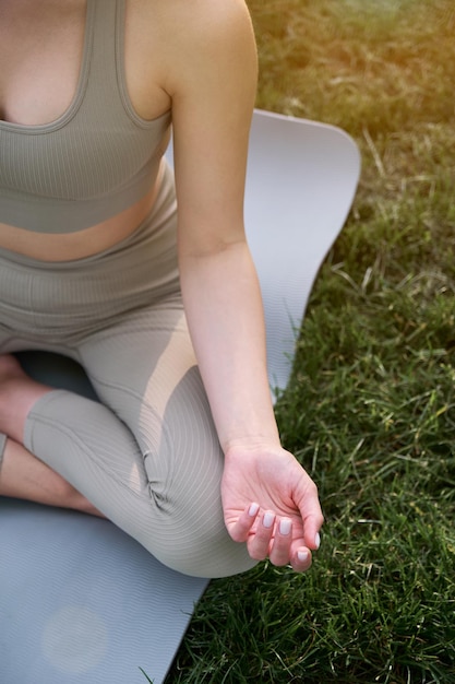 Mains et partie du corps de la femme sur fond d'herbe verte dans le parc Jeune femme médite