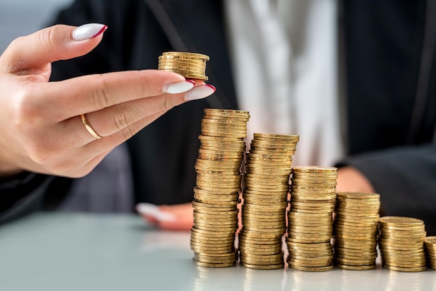 Les mains d'une patronne prennent des pièces d'or d'un tas de pièces sur la table de bureau