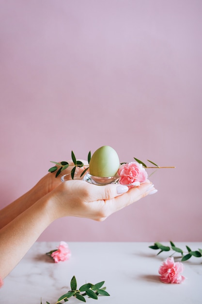 Mains peignant des oeufs de Pâques de style moderne avec de la peinture rose