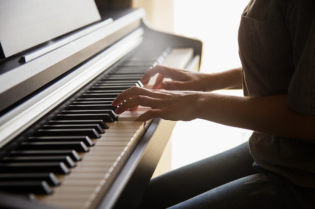 Les mains de la personne caucasienne jouant sur le piano. Concept de loisirs