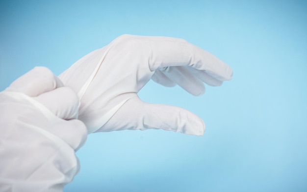 Photo les mains de la personne portant des gants chirurgicaux isolés sur un fond bleu clair