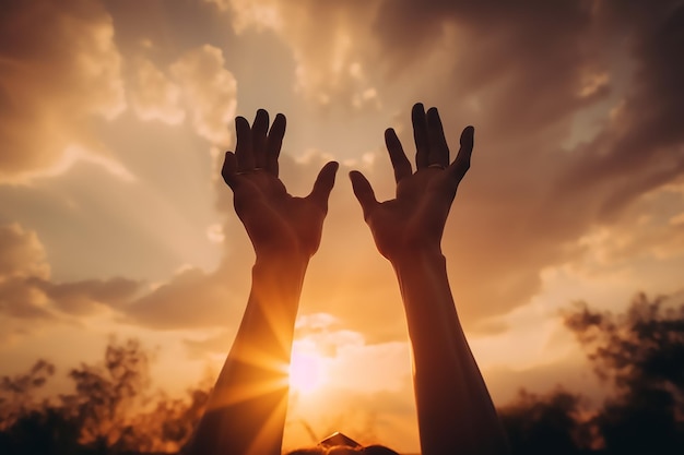 Les mains d'une personne sont levées devant un ciel au coucher du soleil