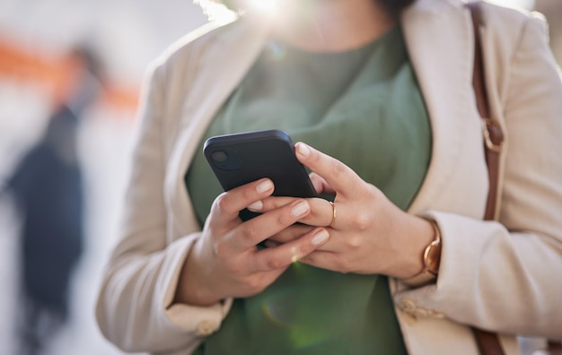 Mains de la personne et un téléphone en plein air pour la communication connexion Internet et application mobile Gros plan d'une femme d'affaires ville urbaine et un smartphone tout en tapant un message ou en discutant sur les réseaux sociaux