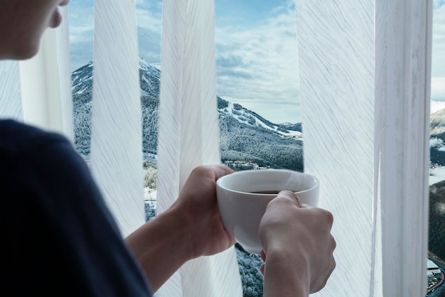 les mains des personnes tiennent une tasse de café chaud en face de la fenêtre à la saison d'hiver b